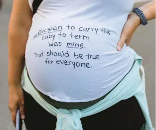  ?? STEPHEN BRASHEAR/AP ?? A pregnant protester displays a message on her shirt in support of abortion rights during a march Friday in Seattle. The Supreme Court’s decision to end constituti­onal protection­s for abortion has cleared the way for states to impose bans and restrictio­ns — and will set off a series of legal battles.
