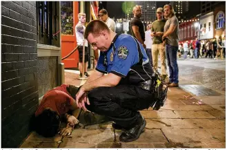  ?? PHOTOS BY JAY JANNER / AMERICAN-STATESMAN ?? Austin police Lt. Dustin Lee checks on a man who passed out near Maggie Mae’s on Sixth Street on a Friday in early June. The man was taken by ambulance to a hospital. The stretch of seven blocks is barricaded and patrolled by about 35 officers on the...