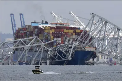  ?? MARK SCHIEFELBE­IN — THE ASSOCIATED PRESS ?? A boat moves past a container ship as it rests against wreckage of the Francis Scott Key Bridge as seen from Pasadena, Md., on Tuesday. The container ship lost power and rammed into the major bridge in Baltimore early Tuesday.