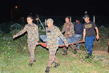  ??  ?? By NATASHA JOIBI and ROYCE TAN newsdesk@thestar.com.my Grim task: Firemen recovering the body of one of the boys at Bukit Beruntung.