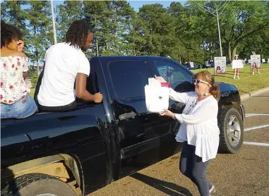  ??  ?? ■ LEFT: Atlanta High Principal Nancy Rinehart congratula­tes senior Keyonte King and gives him a gift bag.