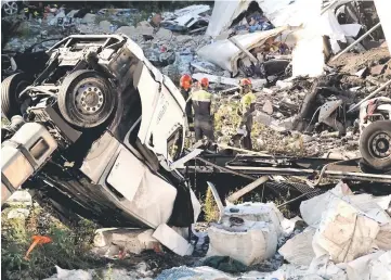  ?? — AFP photos ?? Rescuers inspect the rubble and wreckages by the Morandi motorway bridge after a section collapsed earlier in Genoa.