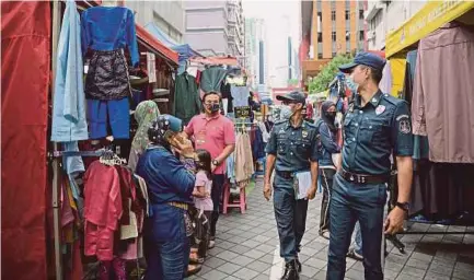  ?? BERNAMA PIC ?? Kuala Lumpur City Hall officers ensuring people’s compliance with the standard operating procedures in Jalan Tuanku Abdul Rahman in Kuala Lumpur yesterday.