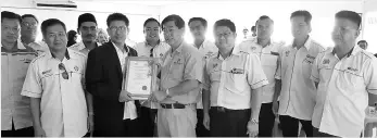  ??  ?? Masly (third left) presenting a souvenir to Yap during the visit while looking on are school principals, headmaster­s and senior assistants.