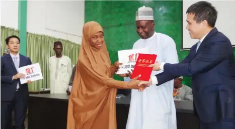  ?? Photo Isa Sa’idu. ?? Chinese Ambassador, Dr. Zhou Pingjian (right) presenting Chinese government scholarshi­p to one of the 47 recipients from ABU, Zaria. Centre is the VC of ABU, Professor Ibrahim Garba.