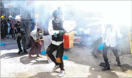  ?? AP ?? Protesters use fire extinguish­ers to counter the impact of the tear gas fired by police Thursday in Yangon, Myanmar.