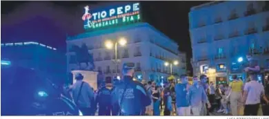  ?? LUCA PIERGIOVAN­NI / EFE ?? Un policía local de Madrid observa a los jóvenes en la Puerta del Sol.