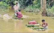  ?? PTI ?? Villagers wade through floodwater­s on a makeshift raft in Nagaon district of Assam on Monday.