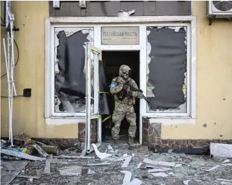  ?? ARIS MESSINIS/AFP VIA GETTY IMAGES ?? A Ukrainian serviceman exits a damaged building Saturday after shelling in Kyiv.