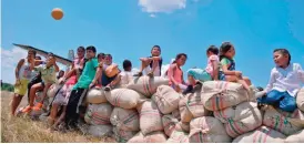  ??  ?? GUERIMA, Colombia: Children sit on sacks of cocoa beans set to be loaded onto a Colombian Air Force plane at the Guerima village airstrip in the municipali­ty of Cumaribo. — AFP