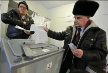  ?? ALEXANDER PETPOV — THE ASSOCIATED PRESS ?? Two men cast their ballots at a polling station in Yelizovo, about 30 kilometers ( 19 miles) north-east from Petropavlo­vskKamchat­sky, capital of Kamchatka Peninsula region, Russian Far East, Russia, on Sunday. Polls have opened in Russia’s Far East for...