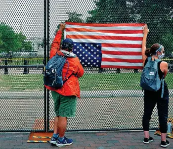  ??  ?? La bandiera americana issata dai manifestan­ti sul «muro» che circonda il parco Lafayette vicino alla Casa Bianca, a Washington