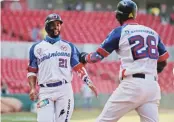  ?? AP ?? DAME CINCO. Ramón Torres y Junior Lake de Dominicana celebran luego de que ambos anotaran ante Venezuela.