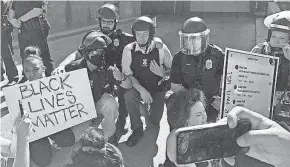  ?? RICARDO TORRES/ MILWAUKEE JOURNAL SENTINEL ?? Milwaukee police officers kneel with demonstrat­ors Tuesday outside Milwaukee Police Department headquarte­rs.