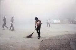  ?? R. S. IYER/ASSOCIATED PRESS ?? Workers sweep dust in morning fog Friday in Greater Noida, near New Delhi. Air pollution remains at hazardous levels in the city.