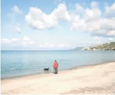  ?? ?? A woman walks with her dog on the beach in the hamlet of Vibo Marina, in Vibo Valentia, Calabria.