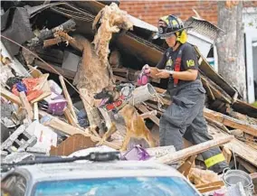  ?? KENNETH K. LAM/BALTIMORE SUN ?? Baltimore fire department K-9 unit working at the scene of an explosion at the 4200 block of Labyrinth Road where multiple rowhouses are destroyed.