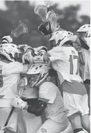  ?? BRIAN KRISTA/CARROLL COUNTY TIMES ?? Teammates jump on C.J. Davidson after the defenseman scored in Glenelg’s win over Century for the Class 2A title.