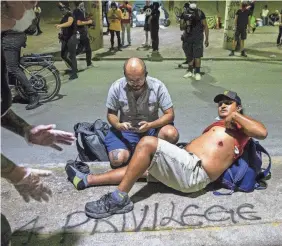  ?? RICARDO B. BRAZZIELL/USA TODAY NETWORK ?? Bystanders come to the aid of a demonstrat­or May 30 after he was shot with a police projectile under the Interstate 35 freeway in Austin, Texas.