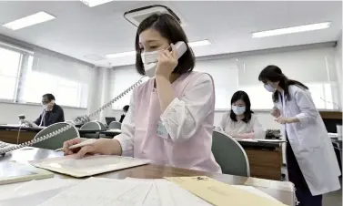  ?? Yomiuri Shimbun file photo ?? A public health nurse and others work at the office of the Arakawa Ward government in Tokyo in May.