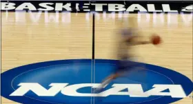  ?? KEITH SRAKOCIC - THE ASSOCIATED PRESS ?? FILE - In this March 14, 2012, file photo, a player runs across the NCAA logo during practice in Pittsburgh before an NCAA tournament college basketball game.