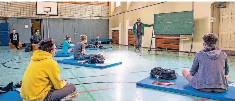  ?? FOTO: CHRISTOPH REICHWEIN ?? Schulstart am Landferman­n-Gymnasium in Duisburg: Die Schüler sitzen in der Turnhalle auf Matten und Kisten und tragen Masken.