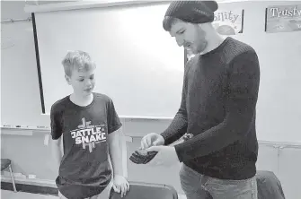  ?? JEFF BELL, TIMES COLONIST ?? Grade 8 student Jacob Smit, left, looks on as designer Alex Burden shows a prosthetic hand. The Victoria Hand Project offers support to amputees in developing countries by giving them prosthetic hands and upper limbs made with 3D printers.