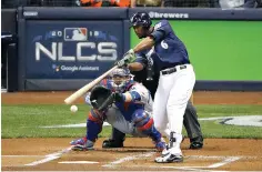  ?? AP Photo/Charlie Riedel ?? ■ Milwaukee Brewers Lorenzo Cain (6) hits a single during the first inning of Game 1 of the National League Championsh­ip Series against the Los Angeles Dodgers on Friday in Milwaukee.