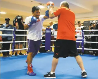  ?? Tertius Pickard / AFP / Getty Images ?? Philippine boxer Manny Pacquiao spars with trainer Freddie Roach in preparatio­n for Pacquiao’s welterweig­ht title defense against Australian challenger Jeff Horn.