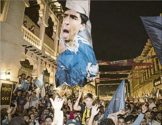  ?? FOTO: J.J. SIRVENT ?? Reunión espontánea de aficionado­s argentinos ayer en el centro de Doha, portando una bandera descomunal con la imagen de Maradona