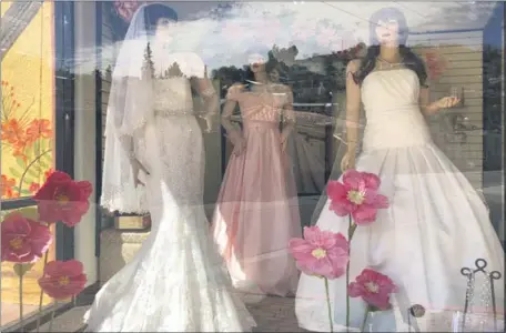  ?? THE ASSOCIATED PRESS ?? Mannequins in wedding gowns are seen in a window display earlier this year at a bridal store in Nogales, Ariz. Couples in the U.S. are racing to the altar in the vaccinatio­n era.