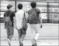  ?? AP/SHIZUO KAMBAYASHI ?? People walk Tuesday near a securities firm in Tokyo where the Nikkei 225 index fell 0.6 percent. Internatio­nal markets were mixed Tuesday as traders dealt with tension on the Korean Peninsula.