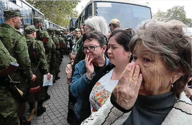  ?? ?? Landesweit werden derzeit russische Reserviste­n eingezogen. Daneben stehen ihre besorgten Mütter und Frauen.