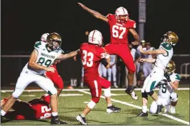  ?? PILOT PHOTO/SUE GARRITY ?? Reggie Vazquez flies for the block on a Wawasee extra point. Devon Bowering of Plymouth looks on.