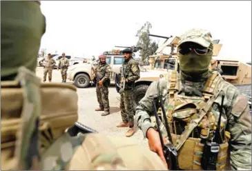  ?? DELIL SOULEIMAN/AFP ?? Members of the Syrian Democratic Forces and US soldiers (left) gather at the al-Tanak oilfield in eastern Syria as they prepare to launch an operation against Islamic State on May 1.