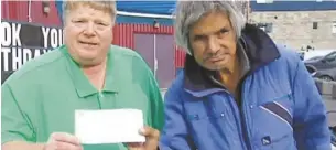  ?? Cbc ?? Charles Delorme, right, hands a cheque to Garry Hubert, executive director of the Sidedoor Youth Centre in Yellowknif­e.