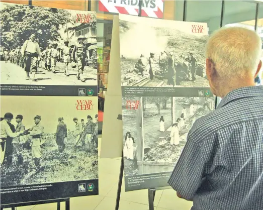  ?? ALDO NELBERT BANAYNAL ?? A senior citizen looks at old war photograph­s displayed in an exhibit as part of the celebratio­n of Philippine independen­ce.