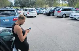  ?? KEVIN SPEAR/STAFF ?? Near the B-52 park at Orlando Internatio­nal Airport recently, ride-share driver Jene Foster checks one of her smartphone apps for the number of drivers ahead of her.
