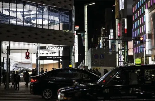  ?? TOMOHIRO OHSUMI/GETTY IMAGES ?? Vehicles drive past a Nissan showroom Tuesday in Tokyo. The arrest in Tokyo of Carlos Ghosn, chairman of the Nissan-Renault-Mitsubishi alliance, has fuelled concerns about the fate of the world’s biggest car pact. Renault’s board appointed the automaker’s No. 2 executive, chief operating officer Thierry Bollore, to temporaril­y fill in for Ghosn.