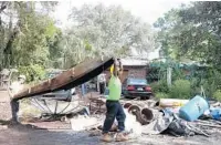  ?? GEORGE SKENE/ORLANDO SENTINEL ?? Workers haul off junk which has accumulate­d over the years at the home of Alan Davis in Altamonte Springs in 2015. Davis currently faces a nearly $1.6 million lien on his property for violating the county’s rules.