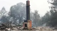  ??  ?? A CHIMNEY STANDS Wednesday amid remains of a home destroyed by the Detwiler fire in Mariposa, California.