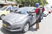  ??  ?? Varios jóvenes limpian los vidrios de un automóvil.