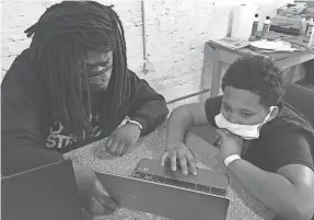  ??  ?? Forrest Jackson, education coordinato­r at Running Rebels Community Organizati­on, helps a child with his virtual schoolwork.