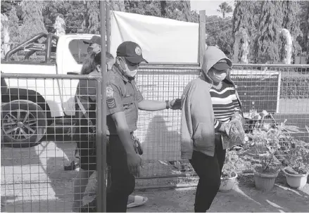  ?? ?? Murder suspect Rudelyn Sumbong is being ushered by a policemen to the New Lucena, Iloilo police station. She is a suspect in the killing of her employer, businesswo­man Claire Diergos in Pavia, IIoilo.