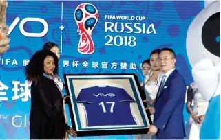  ??  ?? Senior Vice President of Vivo, Ni Xudong, right, holds up a jersey with FIFA's Secretary General, Fatma Samoura during a ceremony to announce the Chinese smartphone brand Vivo's sponsorshi­p of the FIFA soccer World Cup at the Imperial Ancestral Temple...