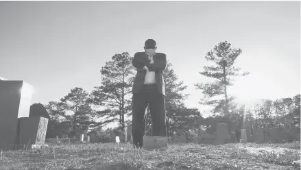  ?? ALLEN G. BREED/AP ?? Mortician Shawn Troy stands at the grave of his father, William Penn Troy Sr., at Hillcrest Cemetery in May outside Mullins, South Carolina.
