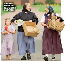  ??  ?? Bruderhof women and a girl walking in their village