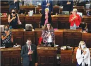  ?? AP FILE PHOTO/CHARLIE NEIBERGALL ?? State representa­tives, some wearing masks, stand at their desks during the Pledge of Allegiance in the Iowa House chambers, at the Statehouse in Des Moines, Iowa.