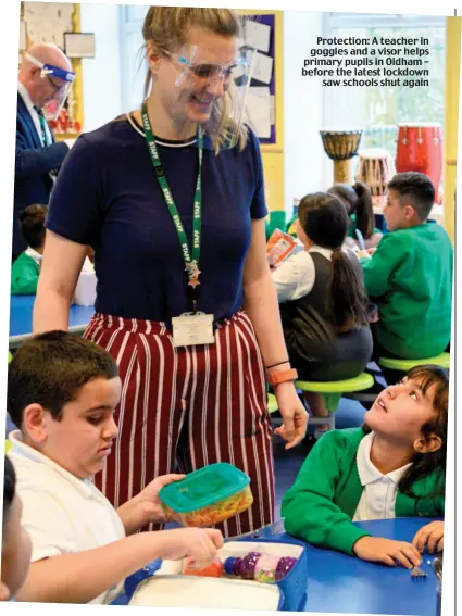  ??  ?? Protection: A teacher in goggles and a visor helps primary pupils in Oldham – before the latest lockdown saw schools shut again