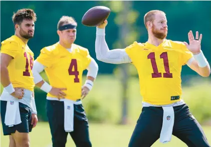  ?? ALEX BRANDON/AP ?? Washington quarterbac­ks Sam Howell, from left, and Taylor Heinicke watch as Carson Wentz throws during practice Thursday in Ashburn. Wentz is expected to play about 15 to 20 snaps in today’s preseason opener against Carolina. Heinicke and Howell are also expected to see action.